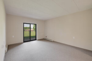 Interior Unit Living Room, Neutral toned carpeting and wall paint, sliding glass patio doors.