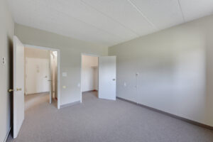 Interior Unit Bedroom, white walls, gray carpeting, walk-in closet.