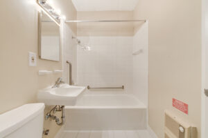 Interior Unit Bathroom, well lit vanity mirror, shower/bathtub, white appliances, tile floor.